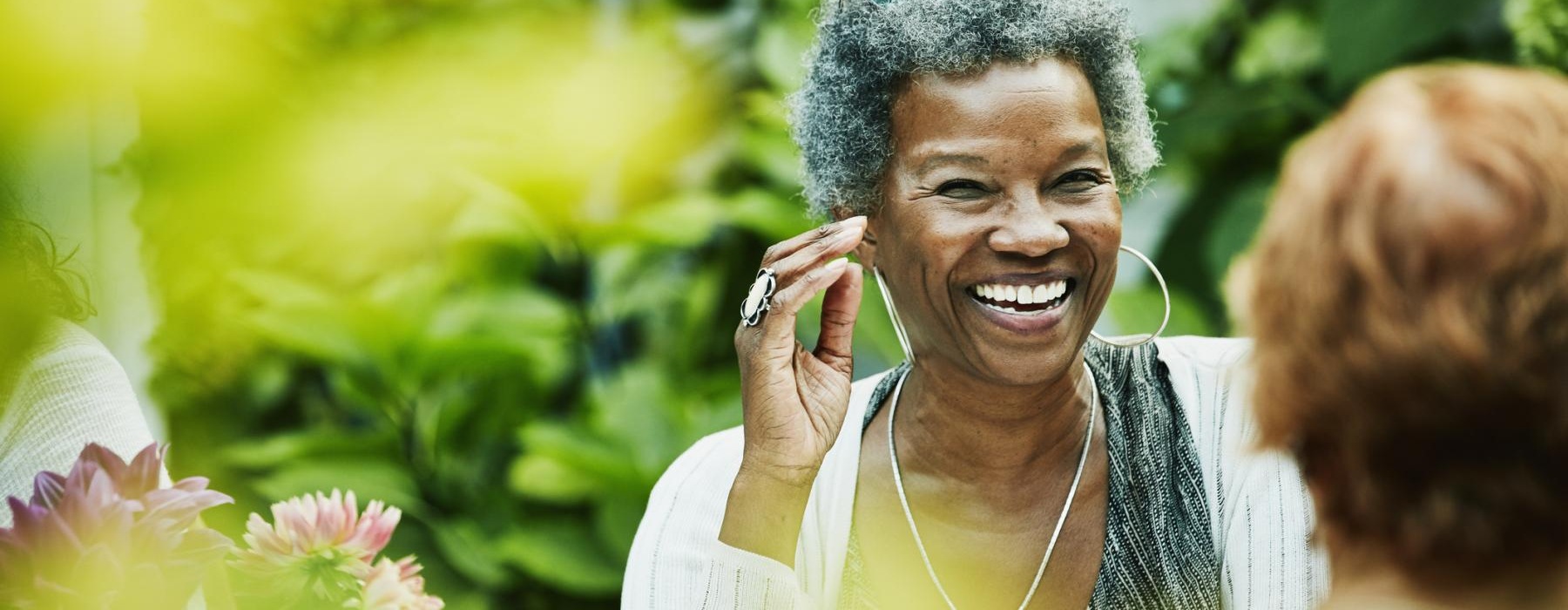 a person smiling with flowers in the back